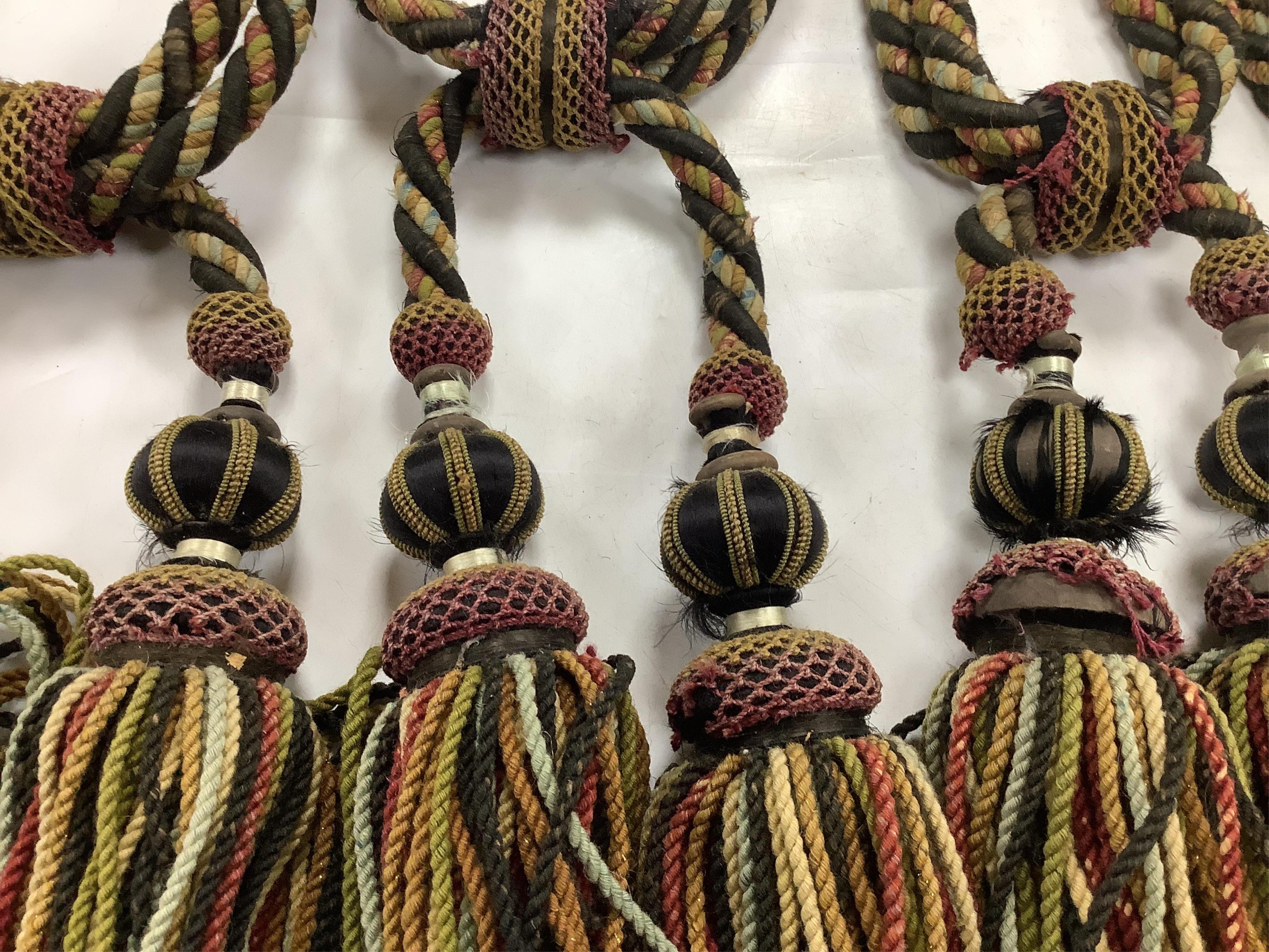 Four pairs of late 19th early 20th century corded and tasseled black and multicoloured tie backs. 69 cm long. Condition - all worn from use and age, one tassel needs repair.